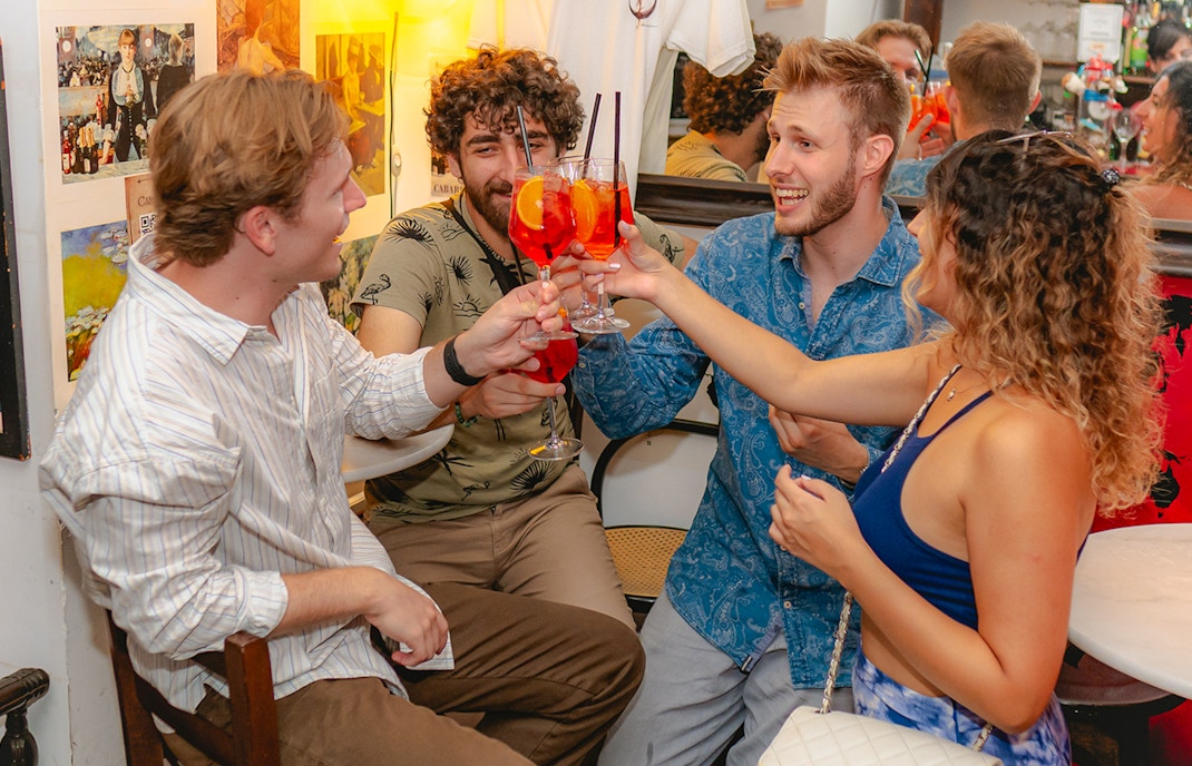 Group of friends enjoying drinks at a lively bar in Rome.