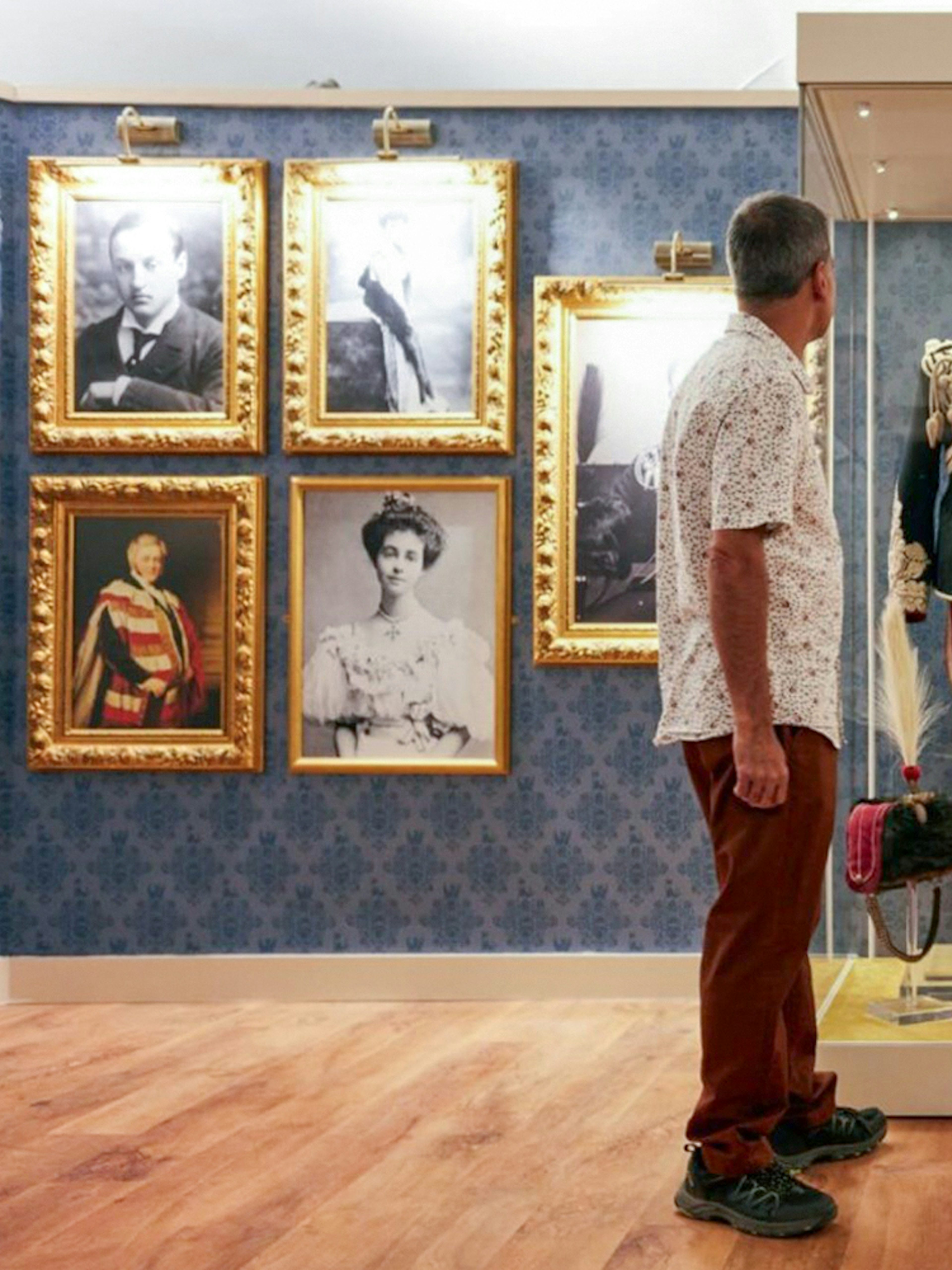 Visitors viewing historical military uniform display at Blenheim Palace State Rooms.