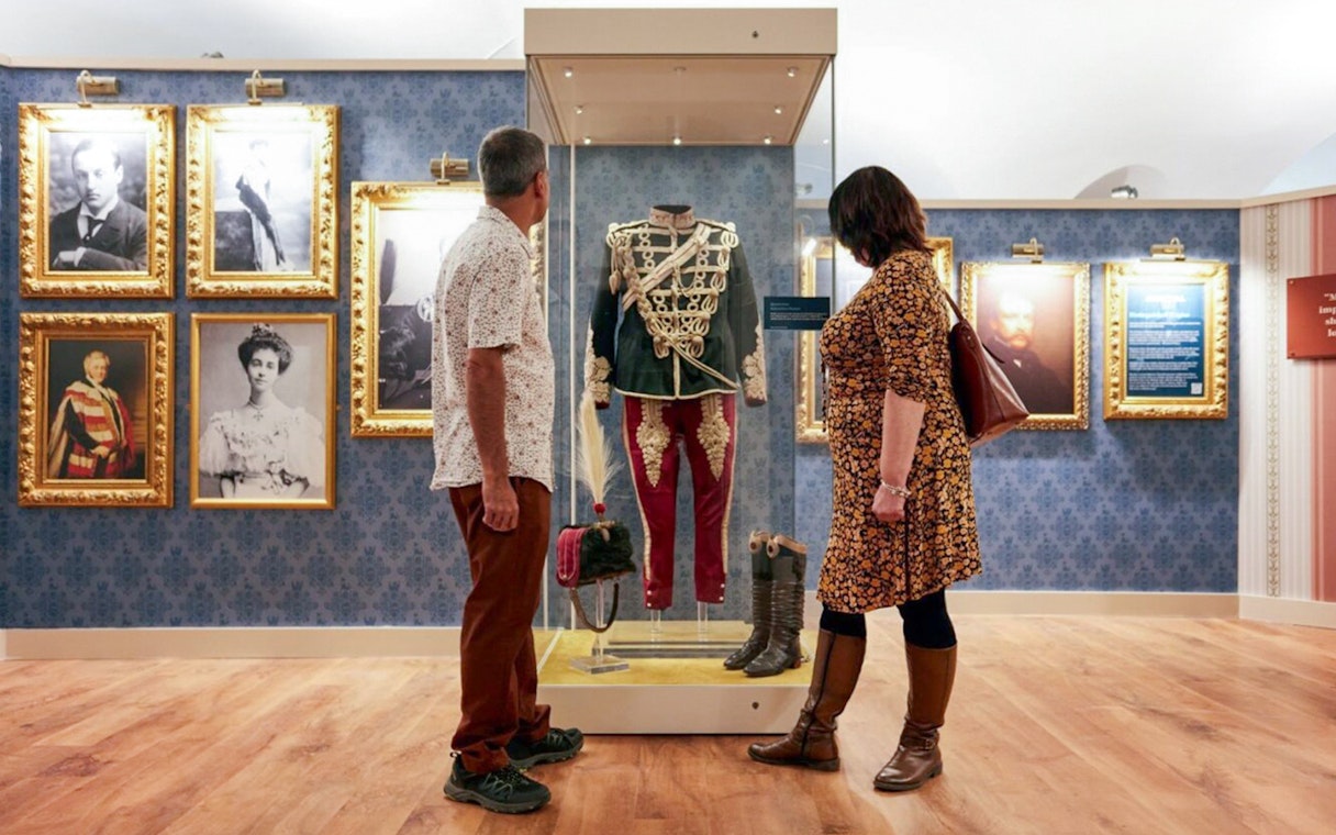 Visitors viewing historical military uniform display at Blenheim Palace State Rooms.