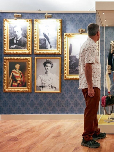 Visitors viewing historical military uniform display at Blenheim Palace State Rooms.