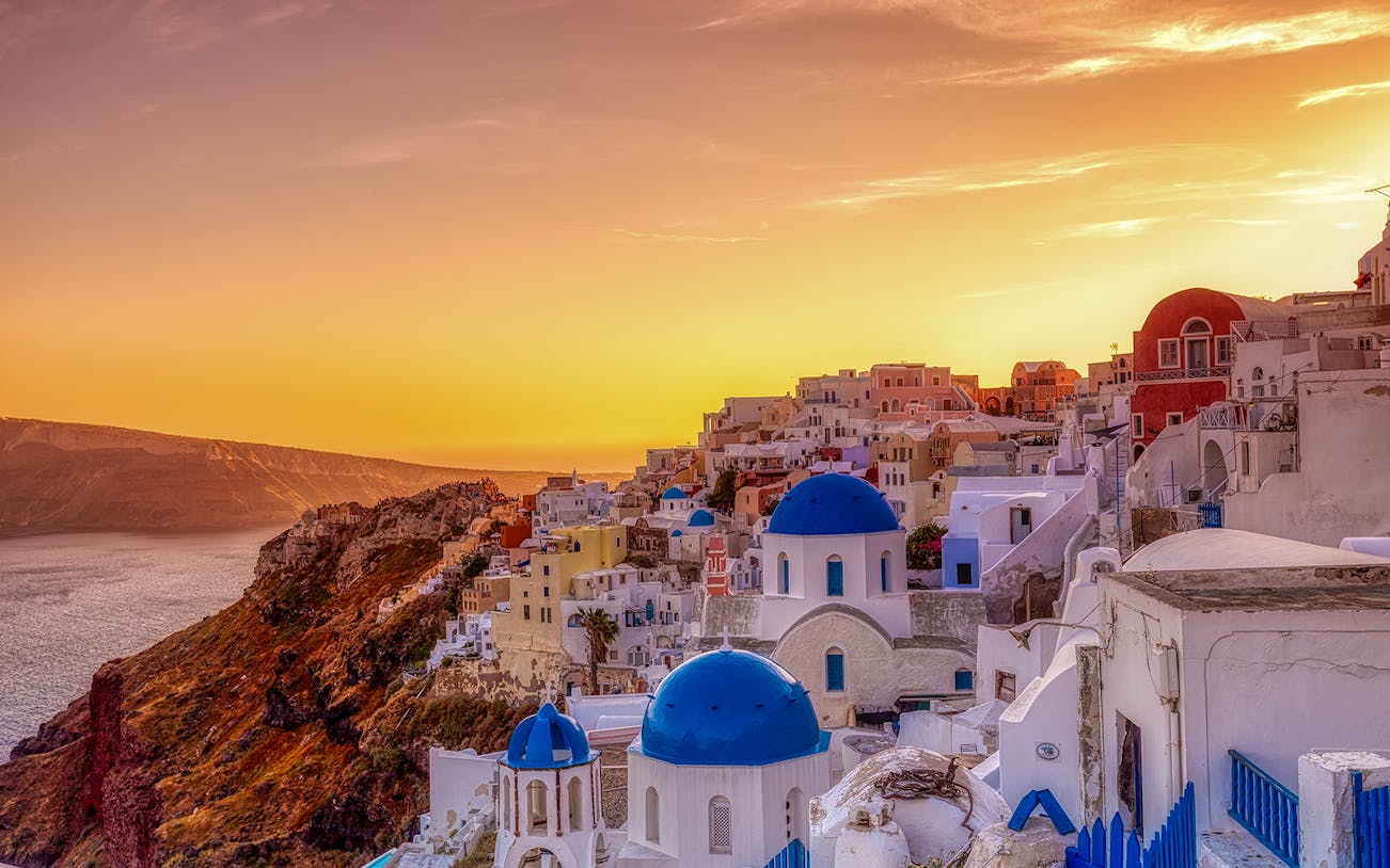 Oia village with blue-domed churches at sunset, Santorini, Greece.