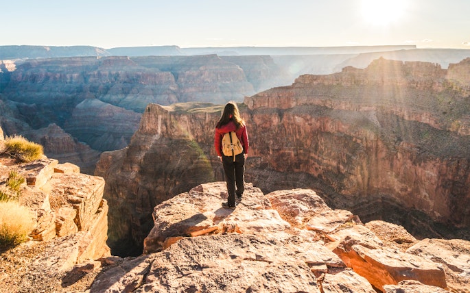 Person standing at the edge of the Grand Canyon, Arizona, overlooking vast canyon views.