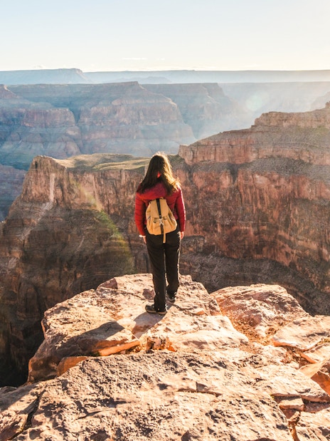 Person standing at the edge of the Grand Canyon, Arizona, overlooking vast canyon views.