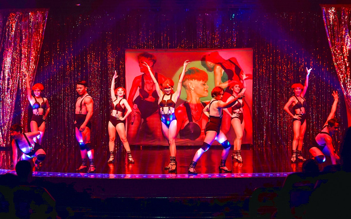 Performers on stage at Calypso Cabaret, Bangkok, in vibrant costumes.