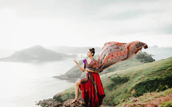 Woman in traditional attire on a cliff overlooking the ocean in Lombok.