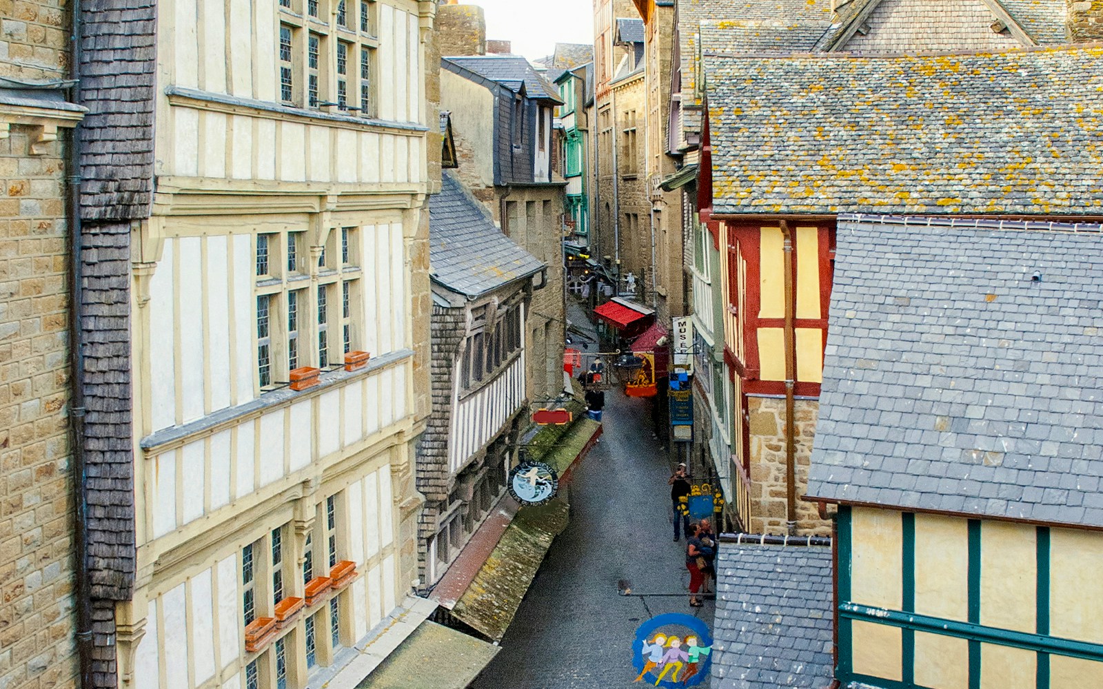 Tourists exploring cobblestone streets of Mont Saint Michel, France, during guided walking tour.