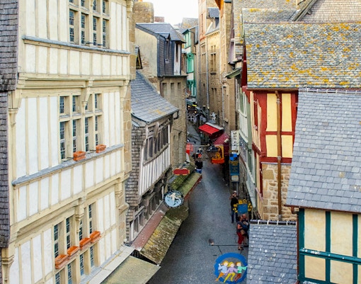 Tourists exploring cobblestone streets of Mont Saint Michel, France, during guided walking tour.