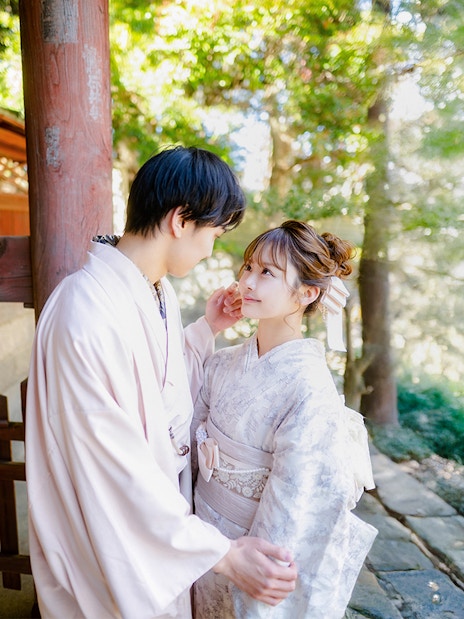 Couple in Yukata posing in a lush green garden with traditional wooden architecture.