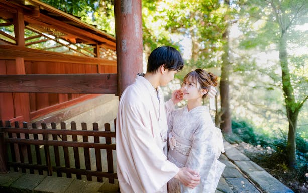 Couple in Yukata posing in a lush green garden with traditional wooden architecture.