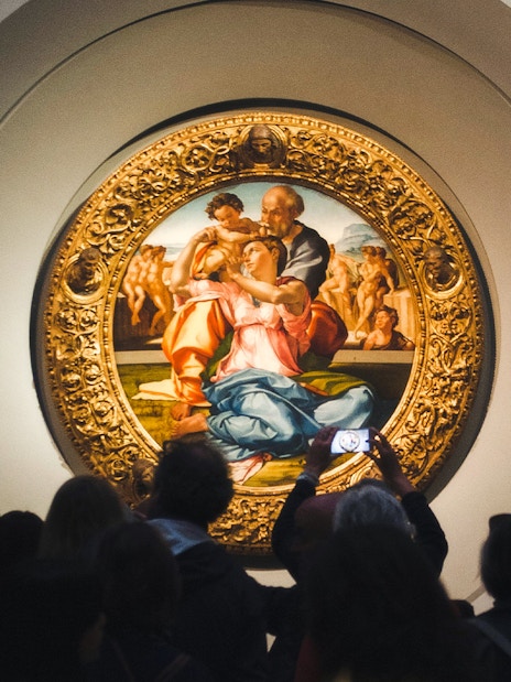 Uffizi Gallery visitors viewing Michelangelo's Doni Tondo painting in Florence.