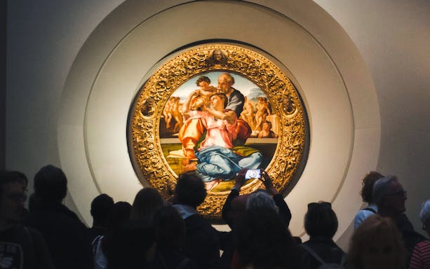Uffizi Gallery visitors viewing Michelangelo's Doni Tondo painting in Florence.