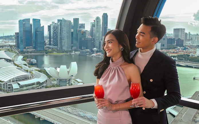 Couple enjoying drinks with a view of Singapore skyline from the Singapore Flyer.