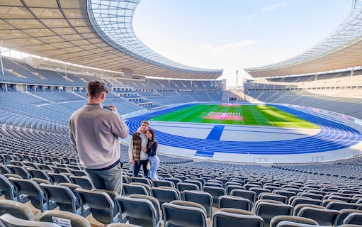Guests taking photos at Olympiastadion Berlin with the stadium in view.