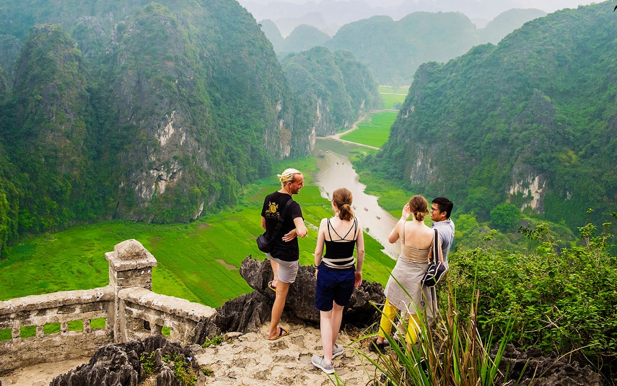 Visitors enjoying the view from Mua Caves lookout point over Tam Coc landscape, Ninh Binh, Vietnam.