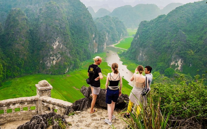 Visitors enjoying the view from Mua Caves lookout point over Tam Coc landscape, Ninh Binh, Vietnam.