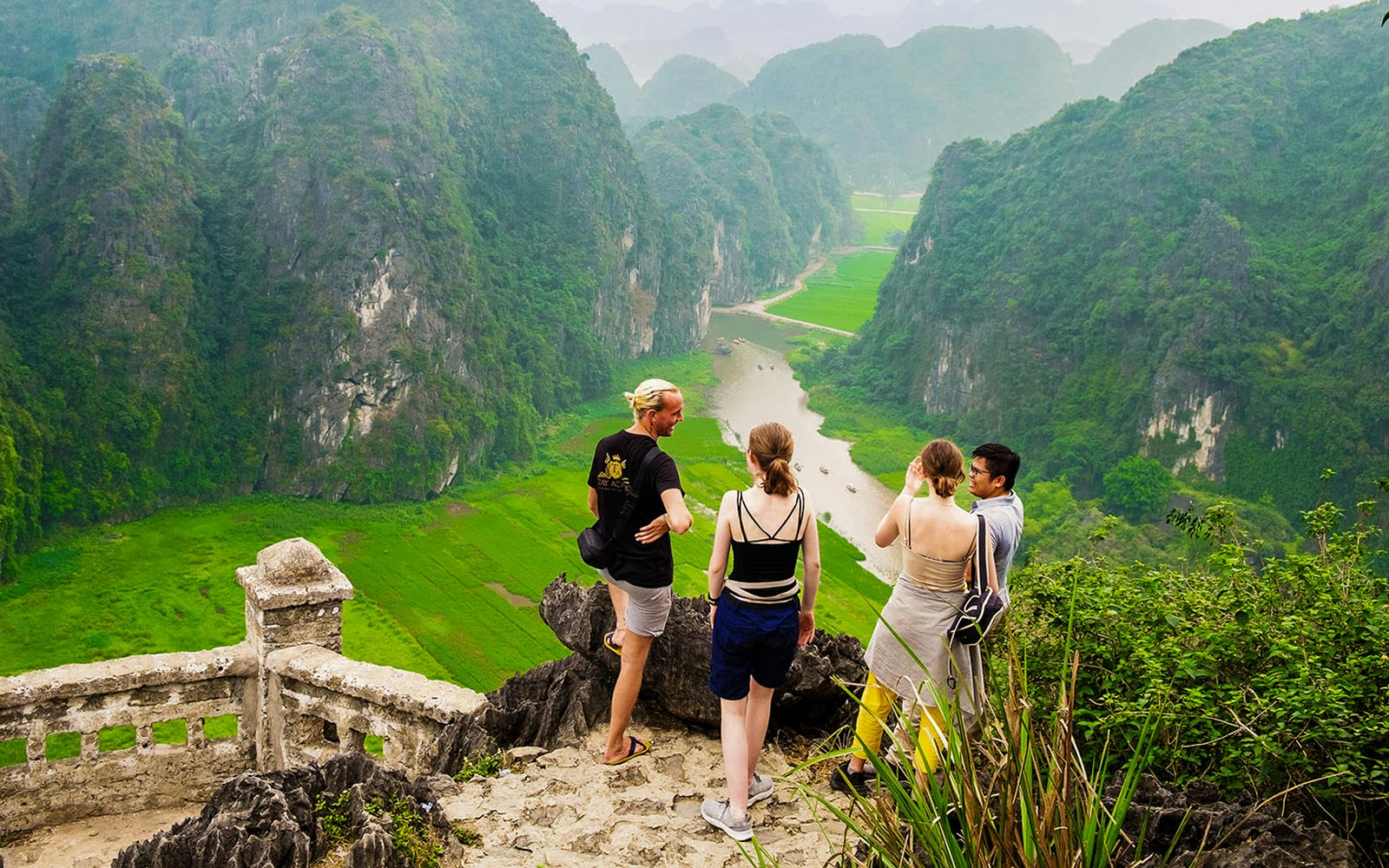 Visitors enjoying the view from Mua Caves lookout point over Tam Coc landscape, Ninh Binh, Vietnam.