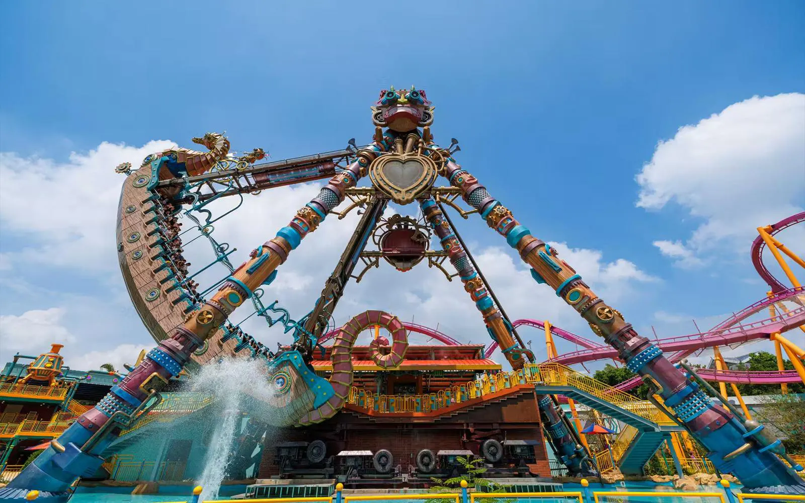 Chimelong Paradise ride with colorful structure and water splash under blue sky.