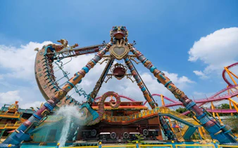 Chimelong Paradise ride with colorful structure and water splash under blue sky.