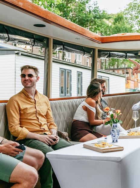 Open boat cruise in Amsterdam with people enjoying drinks and sightseeing.