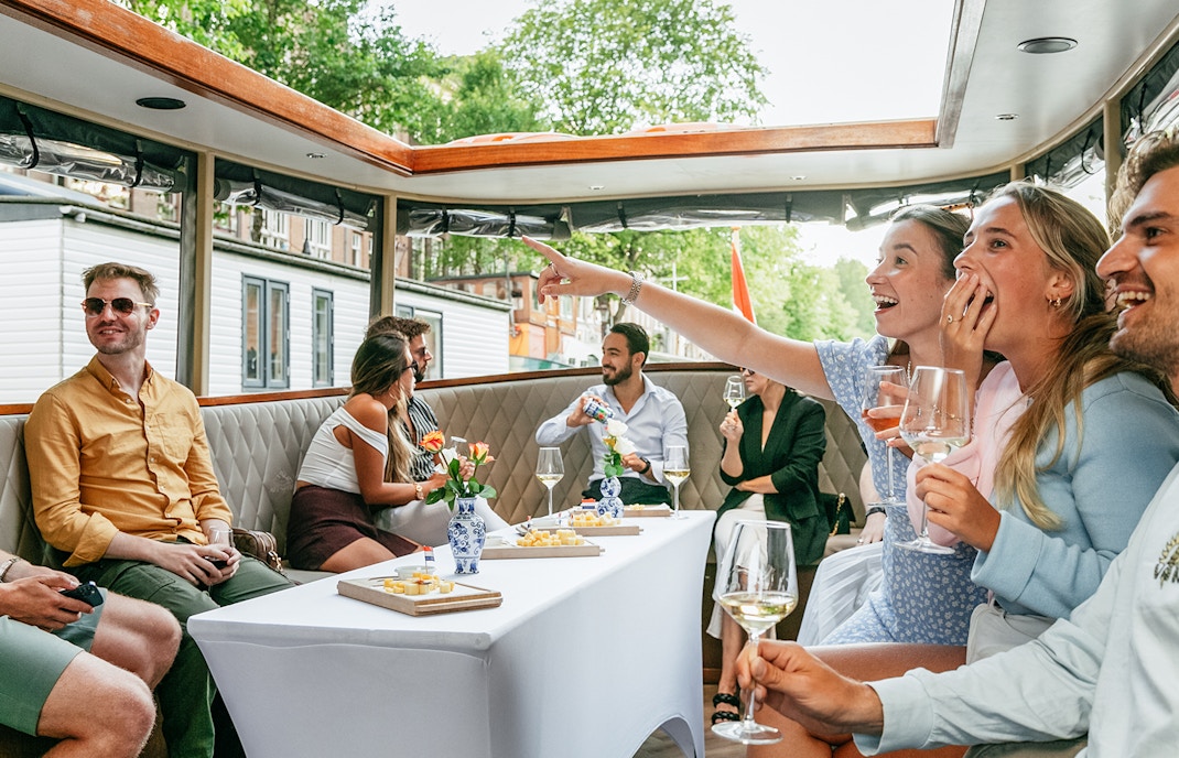 Open boat cruise in Amsterdam with people enjoying drinks and sightseeing.