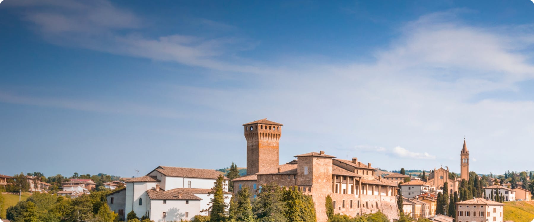 Historic buildings and tower in Maranello, Italy, under a clear blue sky.