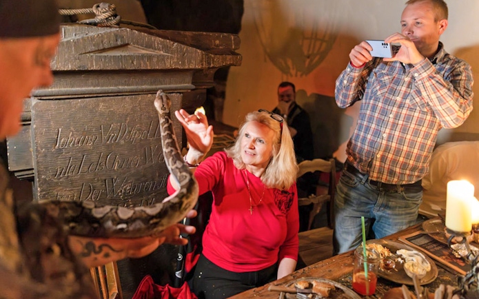 Guests interacting with a snake during a medieval dinner show at Dětenice Brewery near Prague.