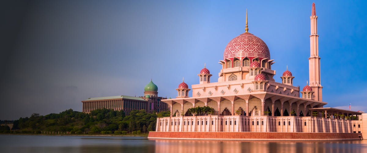 Putrajaya's pink-domed Putra Mosque beside a serene lake in Malaysia.