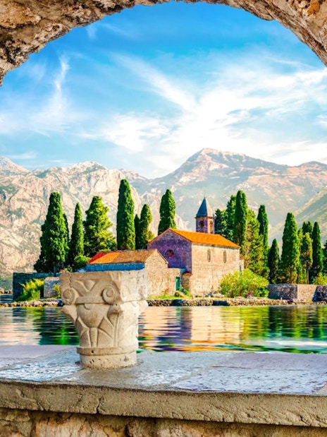 Our Lady of the Rocks island with church, framed by stone arch, Kotor Bay, Montenegro.