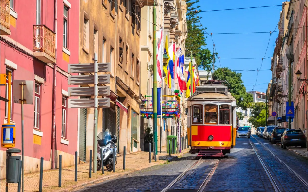Lisbon tram on a colorful street with flags, part of the Fado Murder Mystery city exploration game.