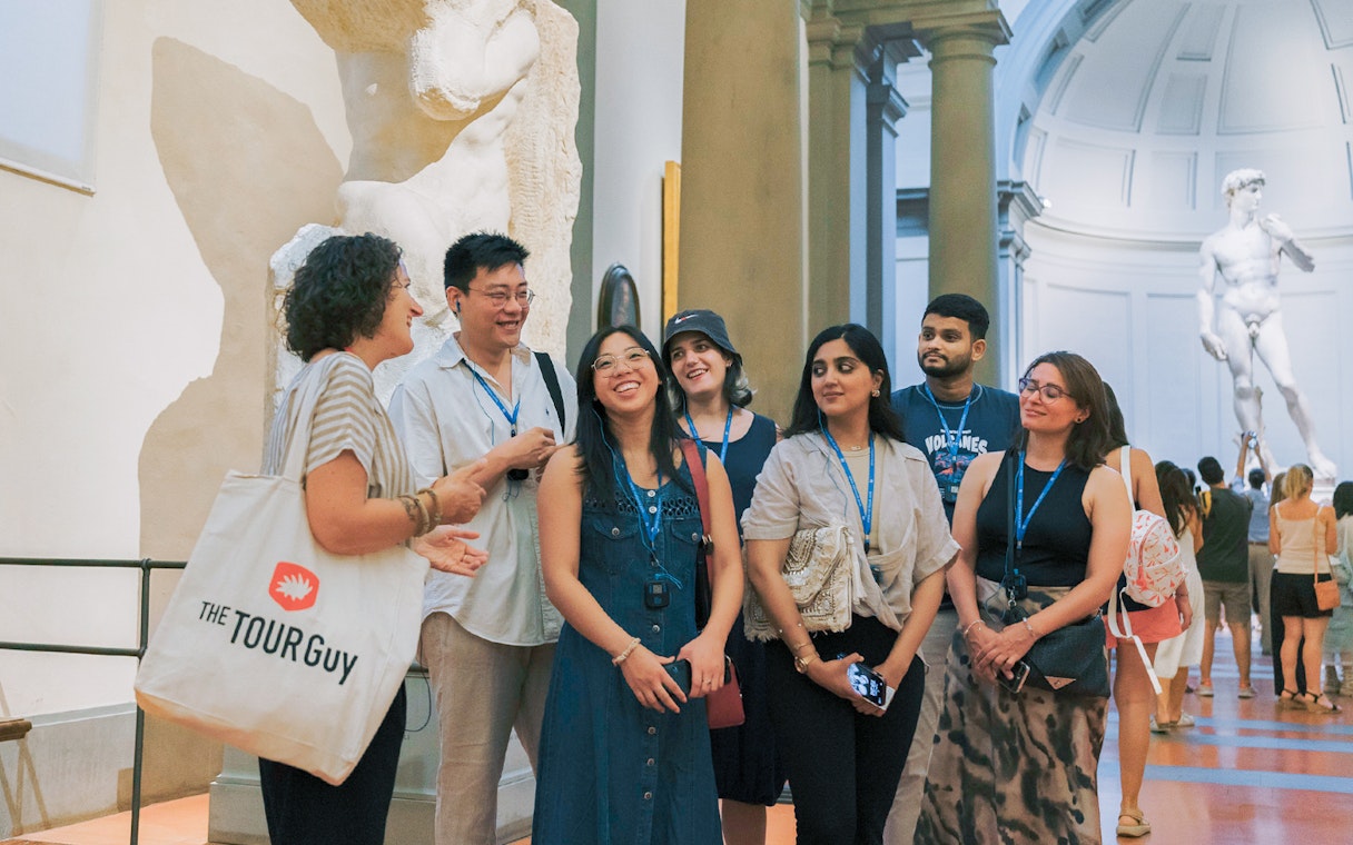 Group tour with guide discussing art in a gallery with sculptures in Florence.