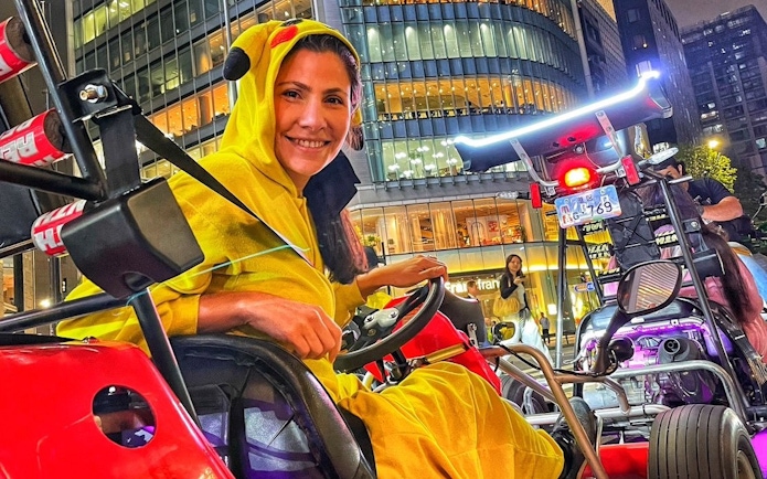 Go-karting tour participant in costume driving through Shibuya, Tokyo at night.