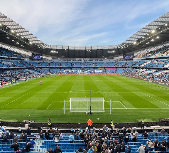 Manchester City Stadium with spectators gathering for a tour.