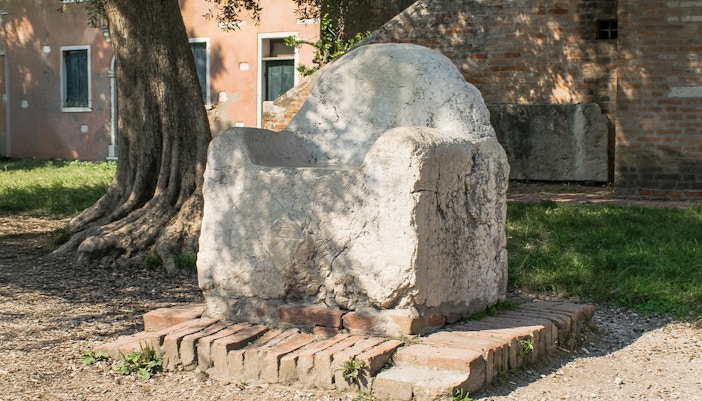 Mysterious stone throne in Venice, known as Attila's Throne, surrounded by historic architecture.