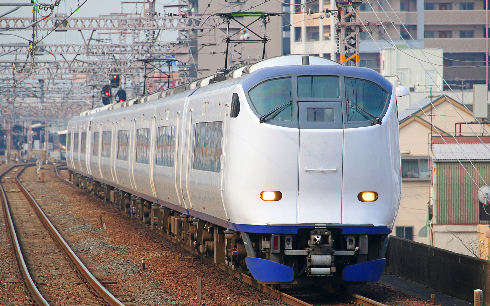 Haruka Kansai Airport Express train on railway tracks in urban Japan.