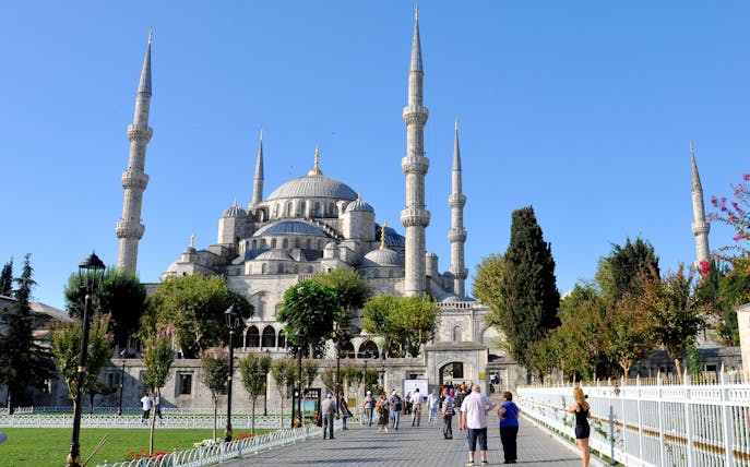 Blue Mosque in Istanbul with visitors walking in the courtyard.