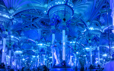 Grévin Paris wax museum hall with mirrored columns and blue lighting.