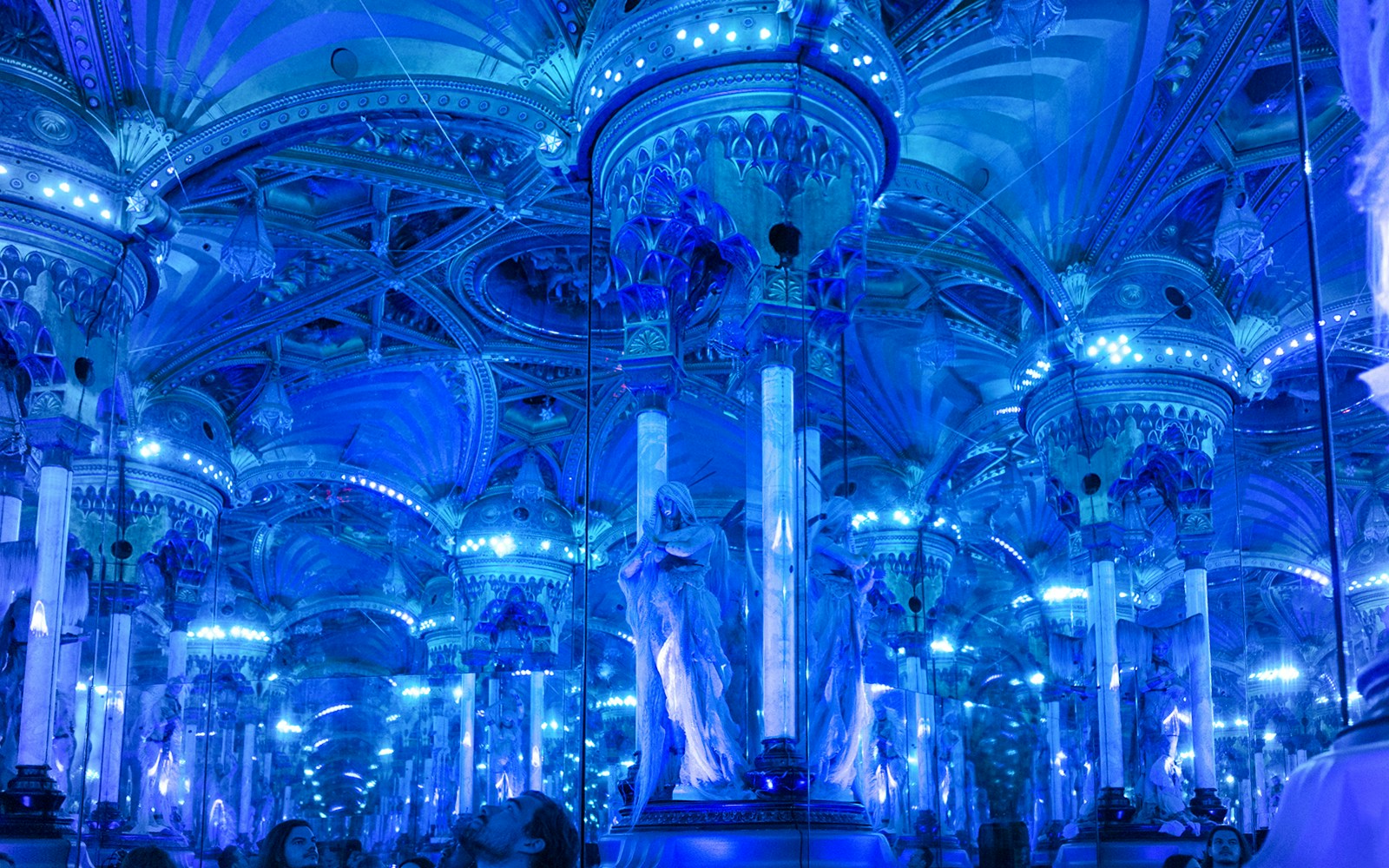 Grévin Paris wax museum hall with mirrored columns and blue lighting.