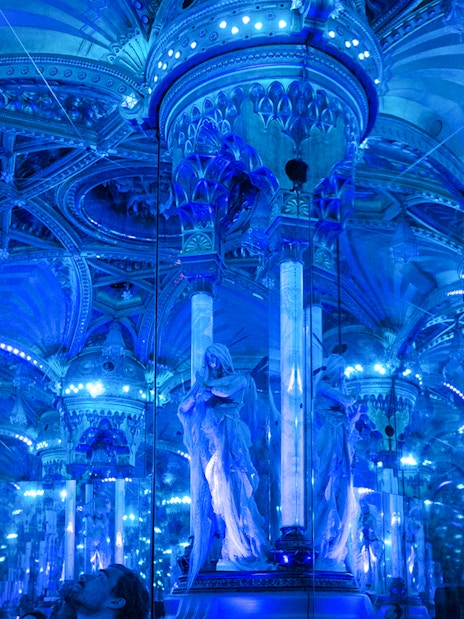 Grévin Paris wax museum hall with mirrored columns and blue lighting.