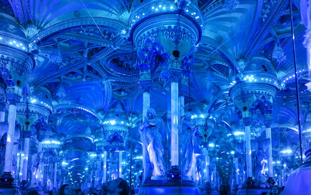 Grévin Paris wax museum hall with mirrored columns and blue lighting.