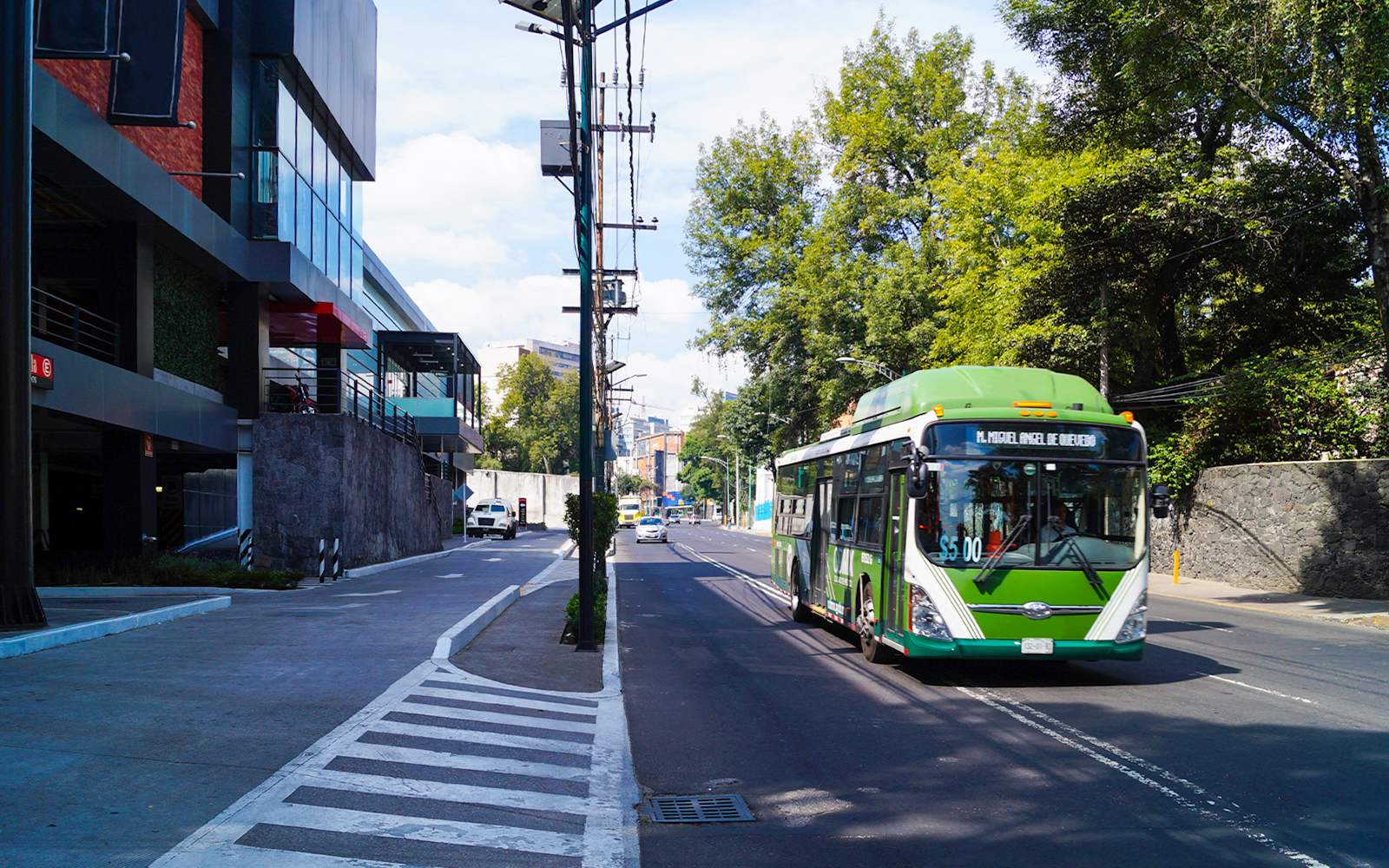 Public transport bus on a busy street in Mexico City with passengers boarding.