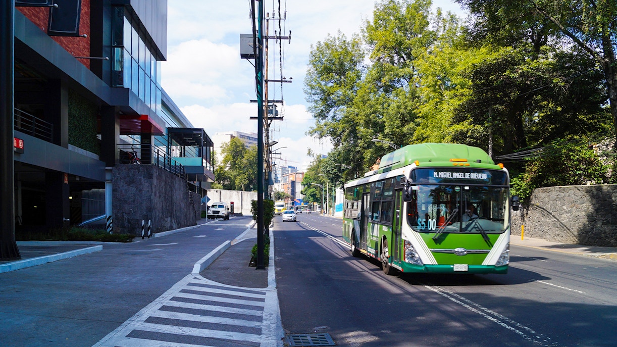 Public transport bus on a busy street in Mexico City with passengers boarding.