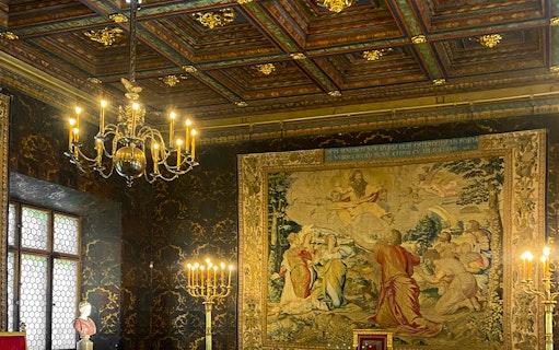 Wawel Castle interior with ornate tapestry and chandelier, Krakow tour.