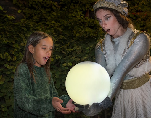 Child and performer holding glowing orb at San Diego Zoo Aurora event.