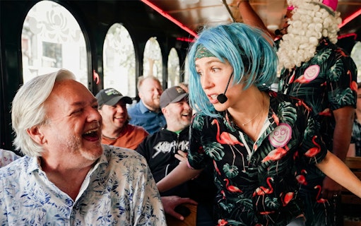 Comedian interacting with laughing passengers on Nashville comedy trolley tour.