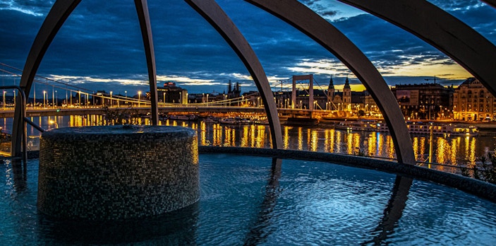Rudas Baths rooftop pool with city lights and river view, Budapest, New Year’s Eve party setting.