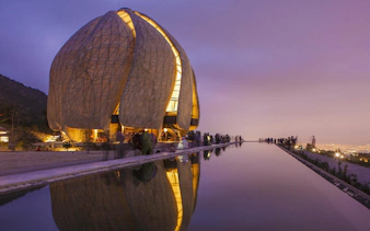 Baháʼí House of Worship in Santiago, Chile, illuminated at dusk with reflection pool.
