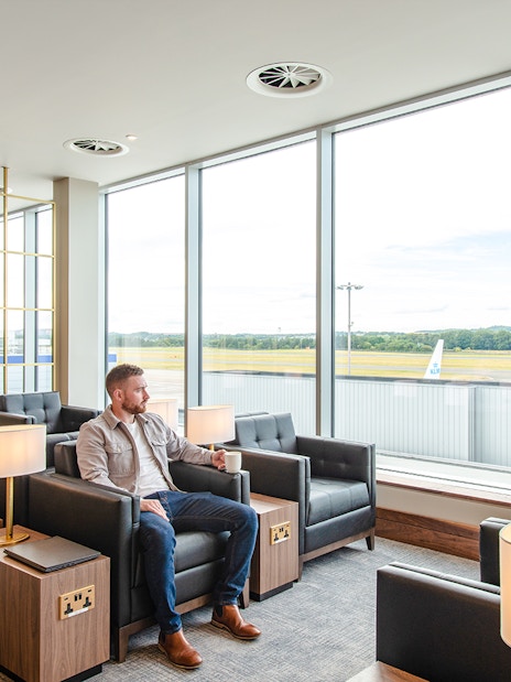Lounge seating area with a view of the runway at Plaza Premium Lounge, Edinburgh Airport.