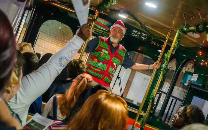 Tour guide in festive attire leading Old Town Trolley's Holiday Sights and Festive Nights Tour, Savannah.