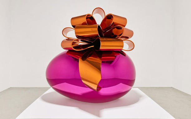 Sculpture of a large pink metallic egg with an orange bow at Moco Museum London exhibit.