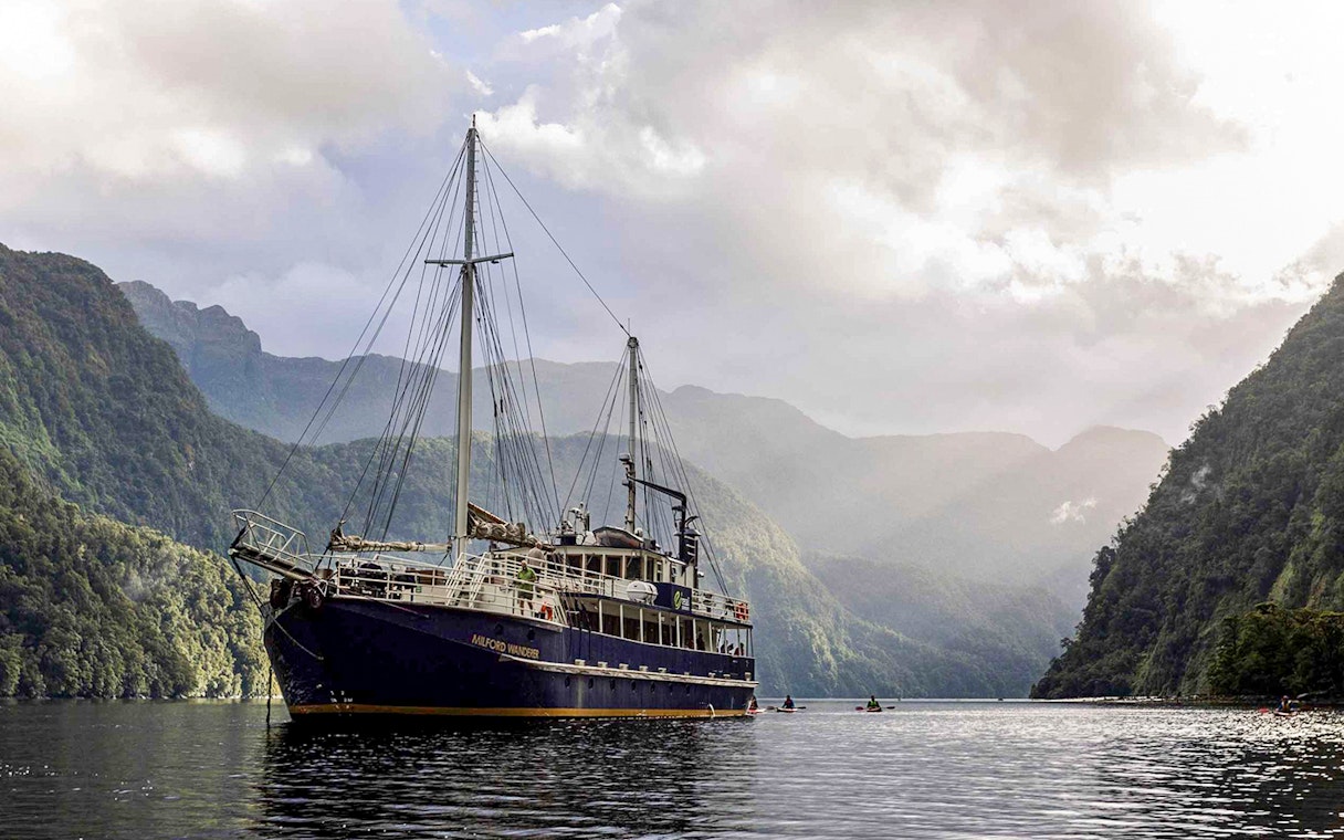Cruise ship on Doubtful Sound surrounded by lush mountains, Te Anau.
